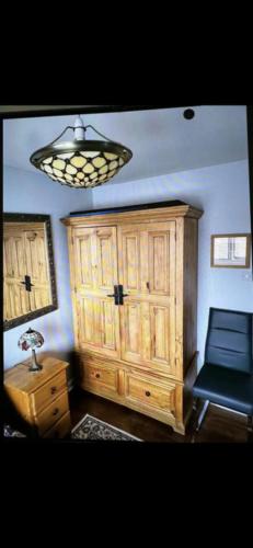 a room with a large wooden cabinet and a lamp at Deluxe Double Bed With Private Mordern Shower & Smart TV in Clydebank