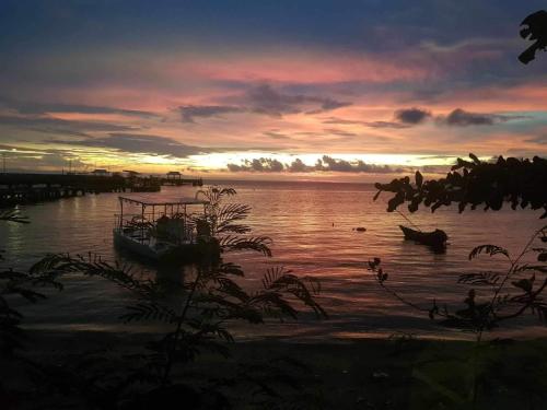 a boat sitting in the water at sunset at The Hut Koh Mak Sea View in Ko Mak