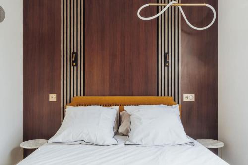 a bed with white pillows and a wooden wall at Luxueux Appartement proche Disneyland in Bussy-Saint-Georges