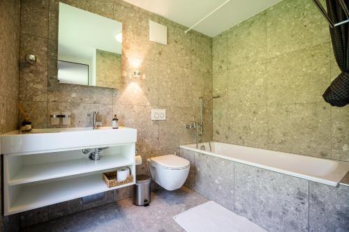 y baño con bañera, aseo y lavamanos. en Haus Burgermeister Wohnung Erzhorn, en Arosa