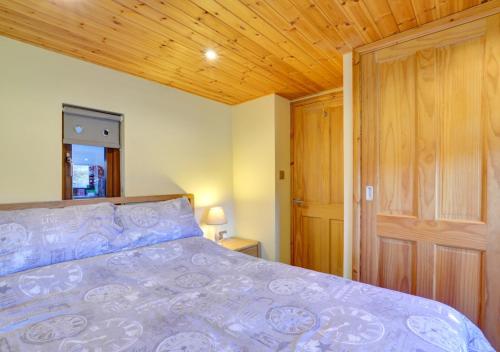 a bedroom with a bed and a wooden ceiling at Lovers' Lodge in Llandegley