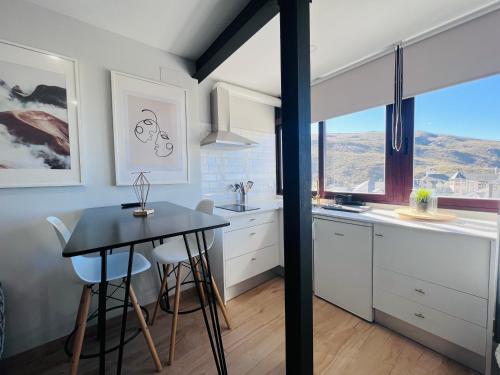 een keuken met een tafel en stoelen en een raam bij Apartamentos Sierra Nevada BlueTTravel - Zona baja in Sierra Nevada