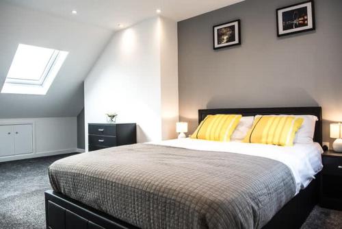 a bedroom with a large bed with yellow pillows at Twickenham Apartments by Charles in Teddington