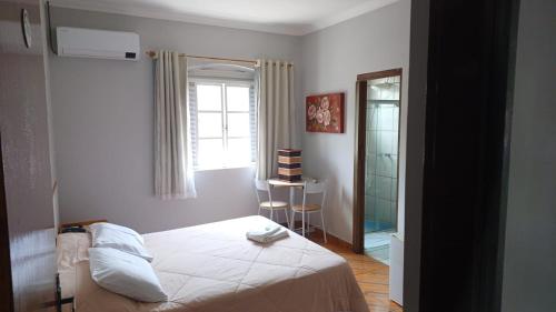 a bedroom with a bed and a window and a mirror at Victoria Hotel - Campanha - MG in Campanha