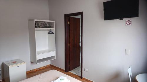 um pequeno quarto com uma televisão e uma porta em Victoria Hotel - Campanha - MG em Campanha