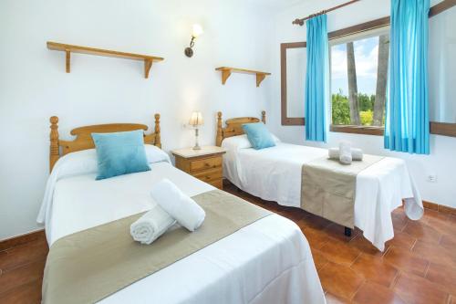 two beds in a room with blue curtains at Villa Conxa Bisanyes by Villa Plus in Alcudia