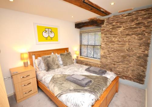 een slaapkamer met een groot bed en een stenen muur bij 5 The Pottery in Dartmouth
