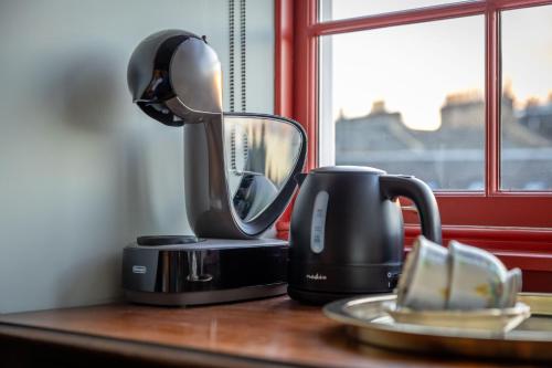 a coffee maker sitting on a table next to a cup at Eleven Stafford Street Townhouse in Edinburgh