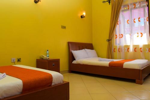 2 camas en una habitación con paredes amarillas en Kipepeo Sky View en Nairobi
