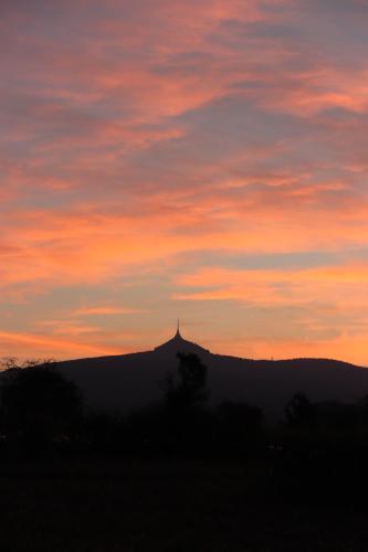 a silhouette of a hill with a sunset in the background at Apartmán MEZI DUBY in Osečná