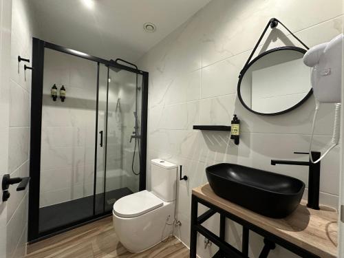 a bathroom with a toilet and a sink and a mirror at CC Opera Suites in Madrid