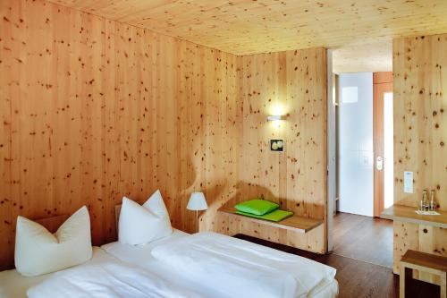 1 dormitorio con 1 cama y pared de madera en Hörger Biohotel und Tafernwirtschaft, en Kranzberg