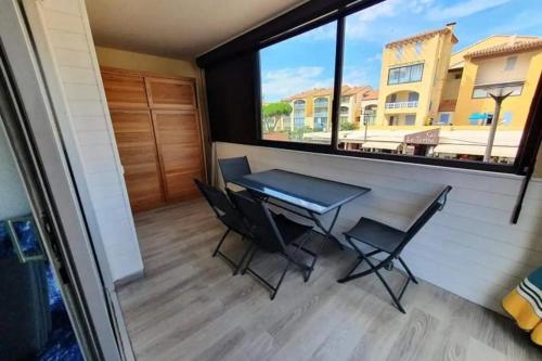 een tafel en stoelen in een tiny house met een groot raam bij pleasant cocoon just a stone's throw from the sea in Le Barcarès
