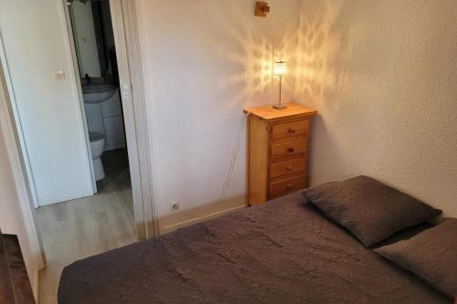 een slaapkamer met een bed en een lamp op een dressoir bij pleasant cocoon just a stone's throw from the sea in Le Barcarès