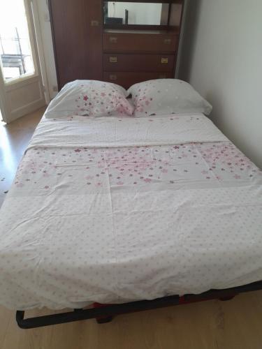 ein Bett mit einer weißen Bettdecke mit Blumen darauf in der Unterkunft Studio meublé avec balcon in Perpignan
