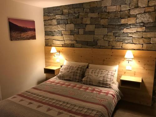 a bedroom with a stone wall with a bed and two lamps at Casa Galèt in Tirano