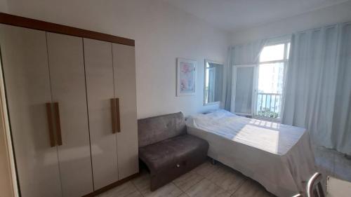 1 dormitorio con 1 cama, armario y ventana en Prado Junior Apartament, en Río de Janeiro