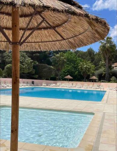 - une grande piscine avec un parasol et des chaises dans l'établissement Agréable Studio Sanary-sur-mer, à Sanary-sur-Mer