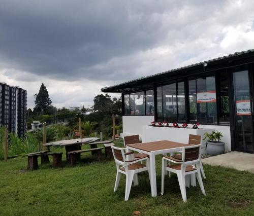 a table and chairs in the grass with a building at APARTAESTUDIO en el Norte de Armenia, en la via a Salento y Filandia Con parqueadero de carro in Armenia