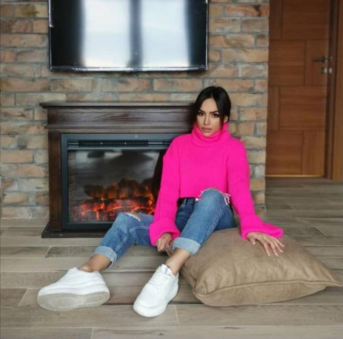 a woman sitting on a pillow in front of a fireplace at Vila Rajski kutak Kopaonik in Kopaonik