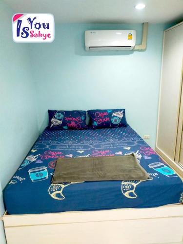 a bed in a room with a blue wall at IsYou Sabye ห้องพักรายวัน รามคำแหง in Ban Zong Katiam
