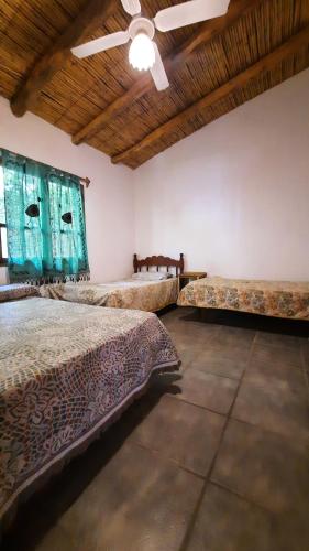 a bedroom with two beds and a ceiling fan at La casona de Adobe in San José