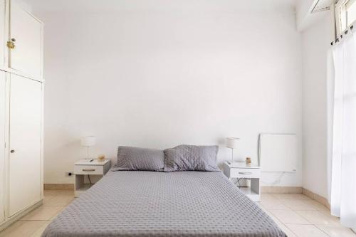 1 dormitorio blanco con 1 cama y 2 mesas en Ideal 3 ambientes c/ homeoffice. Palermo-V.Crespo en Buenos Aires