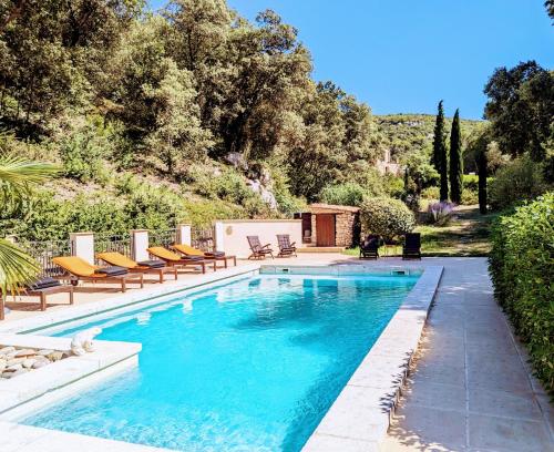 une piscine avec des chaises longues et une maison dans l'établissement La Bergerie Pradel, à Le Beaucet