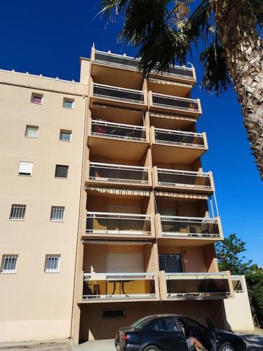 un grand bâtiment avec une voiture garée devant dans l'établissement Studio 4 pers coeur du Lavandou, au Lavandou