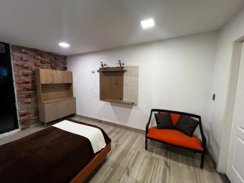 um quarto com uma cama e uma cadeira em TIERRAS ALTAS INN em Tabacundo