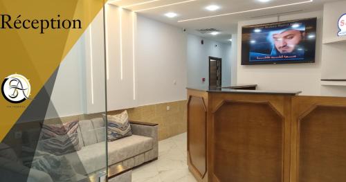 a waiting room with a couch and a tv on the wall at Hostel SA Bab Ezzouar in Le Lido