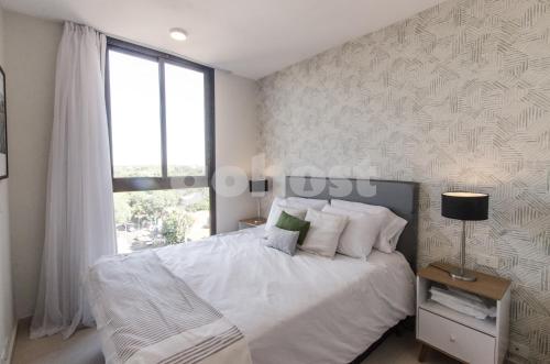 1 dormitorio con cama blanca y ventana en Luxurious And Dazzling Villa Morra Apartment, en Asunción