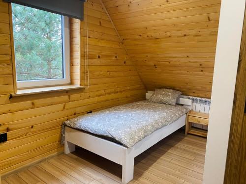 Ce lit se trouve dans une chambre en bois dotée d'une fenêtre. dans l'établissement Sielankowe Pole, à Józefów