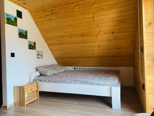 a bed in a room with a wooden ceiling at Sielankowe Pole in Józefów