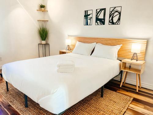 Schlafzimmer mit einem großen weißen Bett mit einem Kopfteil aus Holz in der Unterkunft Sunkissed Boho Hilltop Haven Apartment in San Diego