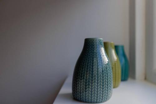 a green vase sitting on a shelf with other vases at 82 Van Road in Caerphilly