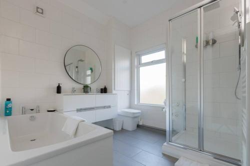 a white bathroom with a tub and a shower at 82 Van Road in Caerphilly