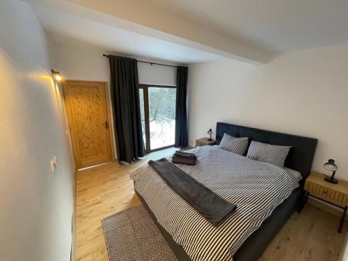 een slaapkamer met een bed met een zwart hoofdeinde en een raam bij Biutiful Bungalow in Vişeu de Sus