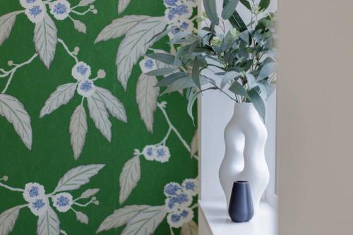 two white vases sitting on a table with a green wallpaper at 82 Van Road in Caerphilly