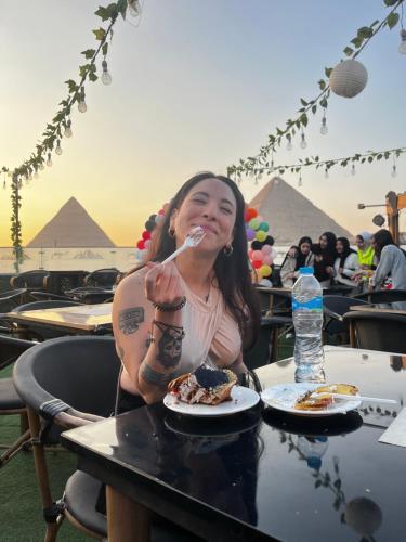 een vrouw die aan een tafel zit eten bij Sahure Pyramid View lnn in Caïro