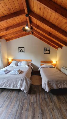 two beds in a room with wooden ceilings and wooden floors at Bellavista in Villa La Angostura