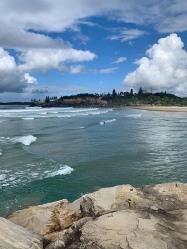 a body of water with rocks and a beach at Tequila Sunset in Yamba