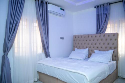 a bedroom with a bed with blue drapes at Still_homes apartment in Kubwa
