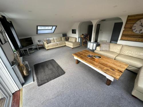 ein Wohnzimmer mit einem Sofa und einem Tisch in der Unterkunft Self Catering Spacious open plan 3 bed apartment with sea views in South Erradale