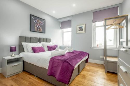 a bedroom with a large bed with purple sheets at Pipeland Loft, Central, Parking in St Andrews