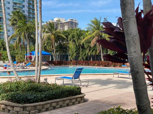 a swimming pool with two chairs and palm trees at Sunny Isles, beach life! Parking included in Miami Beach