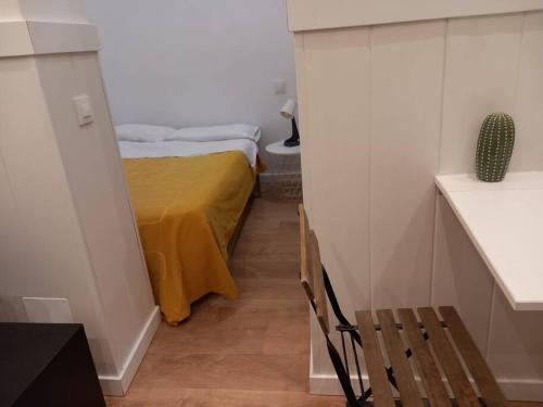 a small room with a bed with a yellow sheet at Bonito estudio en Madrid centro in Madrid