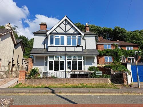 a white house with blue windows on a street at Manse Apartment in Great Malvern