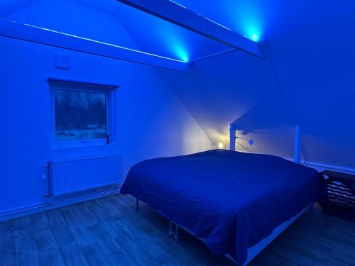 a blue bedroom with a bed and a blue light at Sjöutsikt, Röd trästuga med traditionellt yttre Skandinavisk, modernt inre och alla bekvämligheter, Sol hela dagen på stora altanen, Tryggt, Vinterbonat, Fiske, Båt in Skinnskatteberg