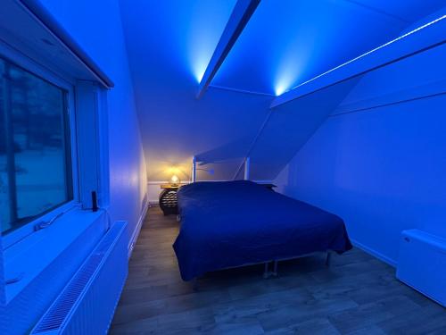 a blue room with a bed and a window at Sjöutsikt, Röd trästuga med traditionellt yttre Skandinavisk, modernt inre och alla bekvämligheter, Sol hela dagen på stora altanen, Tryggt, Vinterbonat, Fiske, Båt in Skinnskatteberg